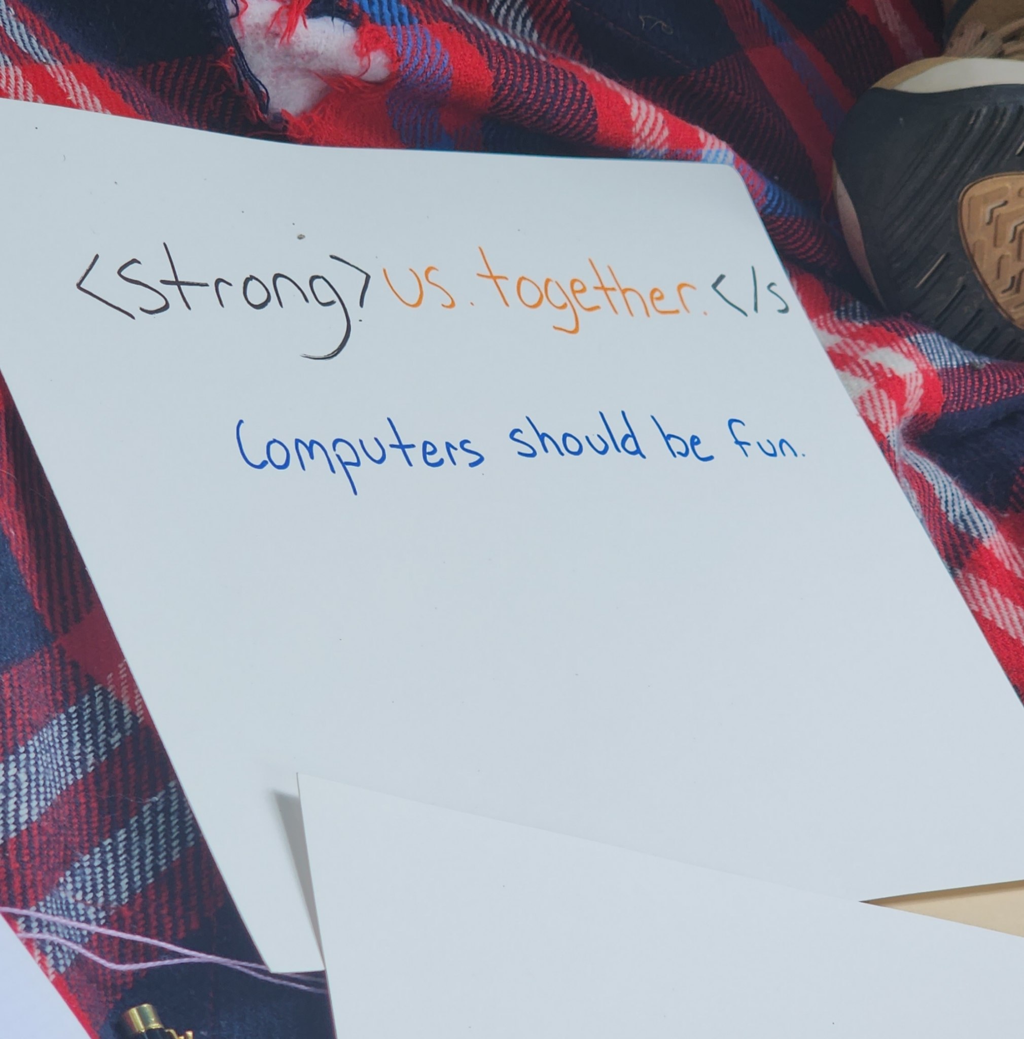 A piece of paper with a handwritten note stating that we are strong together, with a reference to the HTML strong tag. Beneath it, a statement that computers should be fun.